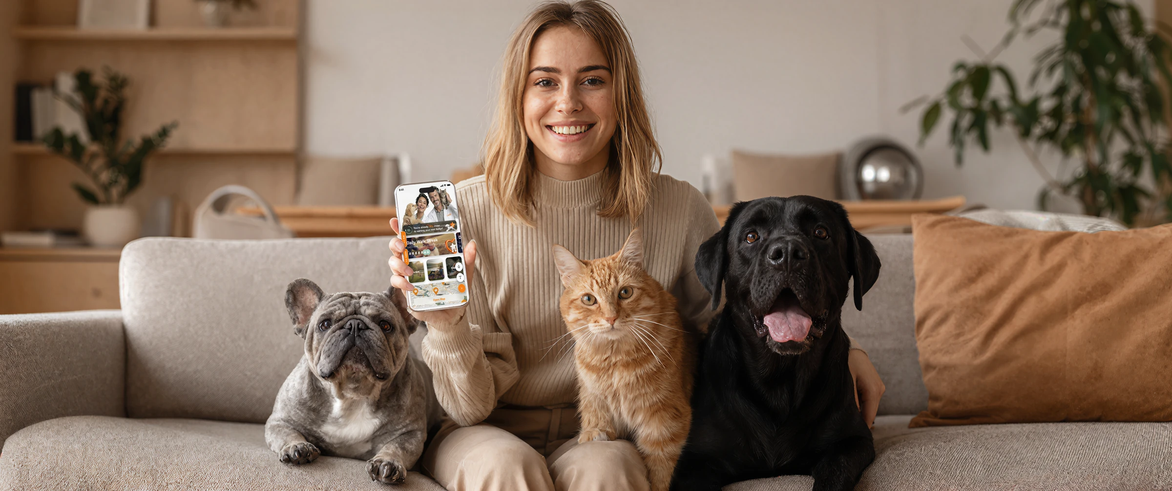 A pet owner holding the FitFur app with her cat and two dogs